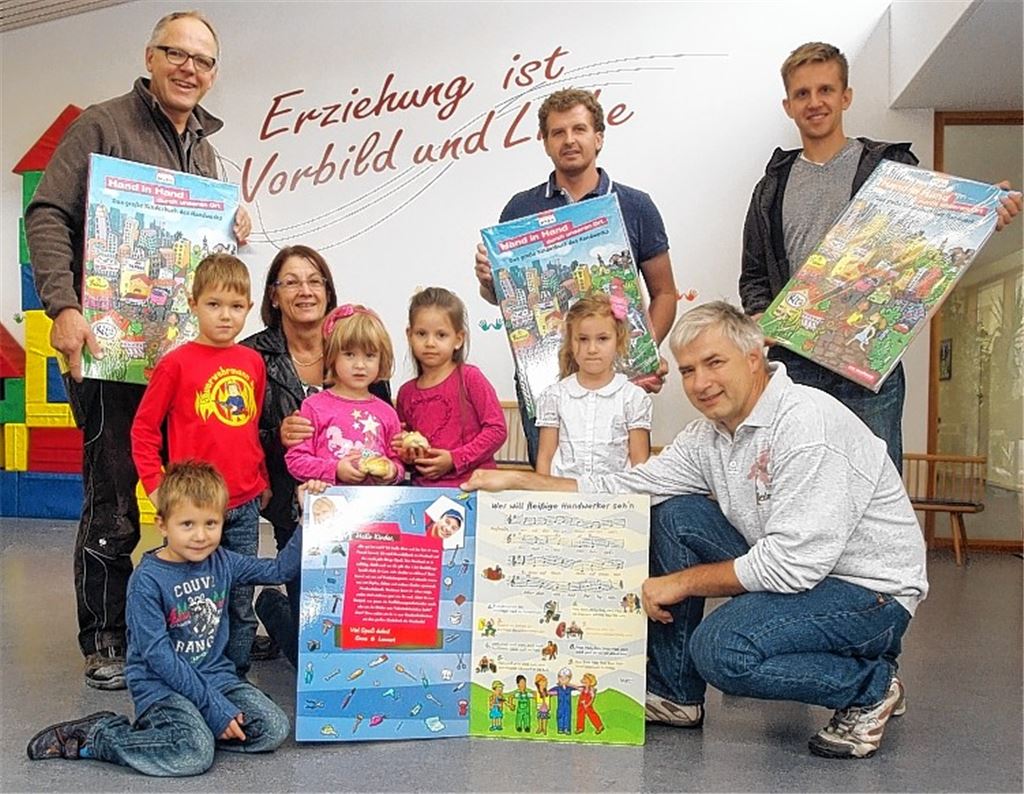 Marko Merkle (Stukkateur und Maler), Andreas Schwing (Maler, hinten v. re.), Ralf Koch (Schreiner, hinten li.) und Martin Reinhardt (Bäcker, vorne re.) übergeben im Knittlinger Kindergarten das überdimensionale Handwerker-Buch an Leiterin Marie-Luise Rohde.