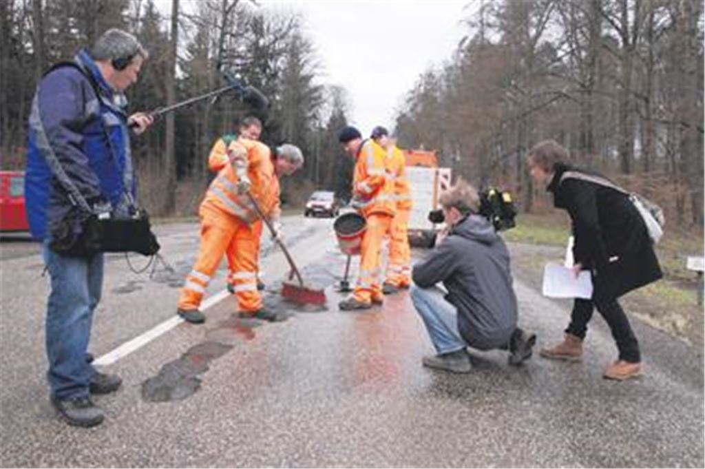 Marode Holperpiste und mieses Wetter als perfekte Drehbedingungen: Für ihre rund dreiminütige Reportage über die schlechten Straßenverhältnisse im Kreis nimmt sich ein Fernsehteam des SWR zwei Stunden Zeit. Zwischen Ellmendingen und Auerbach schaut Reporterin Marie-Kristin Boese (re.) den Mitarbeitern der Enzkreis-Straßenmeisterei bei ihrer Flickarbeit über die Schulter. Foto: Disselhoff
