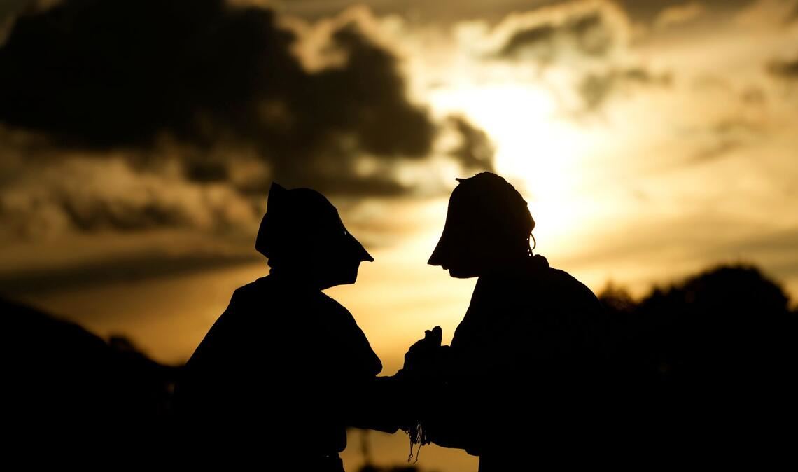 Maskierte Freischärler schauen sich bei Sonnenuntergang eine traditionelle Reitershow an.
