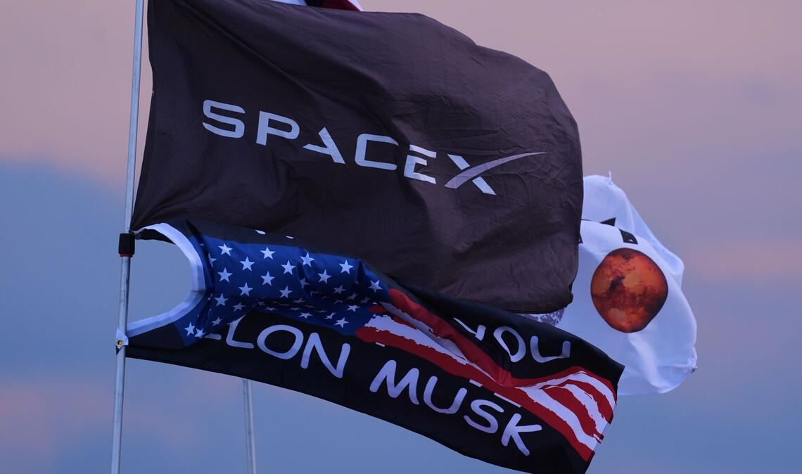 Zehnter Testflug von Rakete Starship um einen Tag verschoben Mehrere Fahnen, darunter zwei mit dem Aufdruck SpaceX und Elon Musk, sind in der Nähe des Startortes.