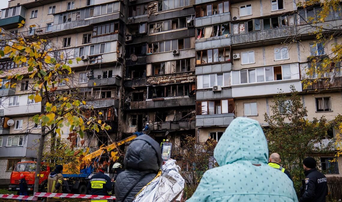 Bilder des Tages Menschen beobachten die Arbeit der Feuerwehr in einem zerstörten Wohnhaus nach einem russischen Drohnenangriff.