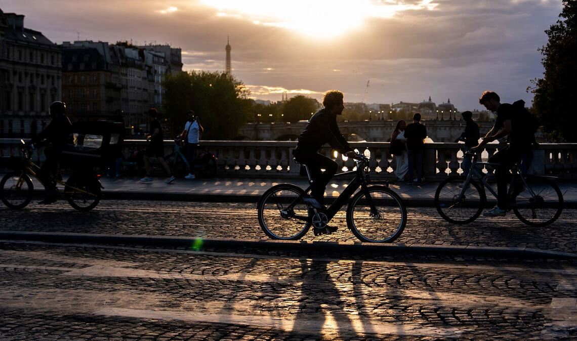 Bilder des Tages Menschen fahren bei Sonnenuntergang mit dem Fahrrad auf einer Brücke über die Seine in Paris.