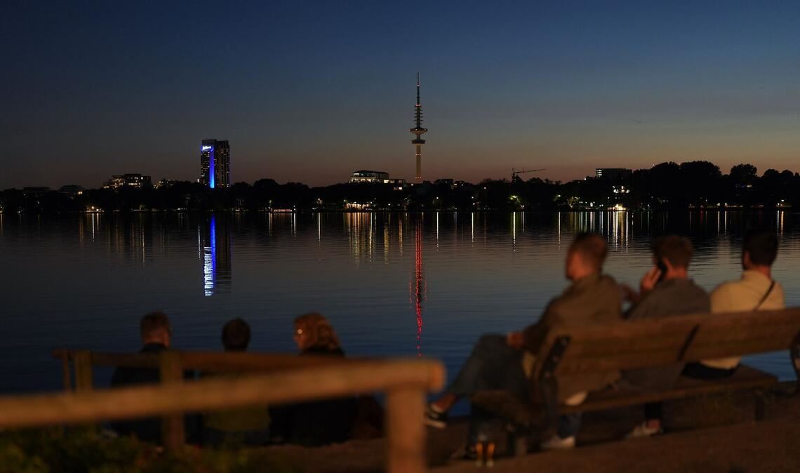 Menschen genießen die Abendstimmung am Ufer der Außenalster in Hamburg.