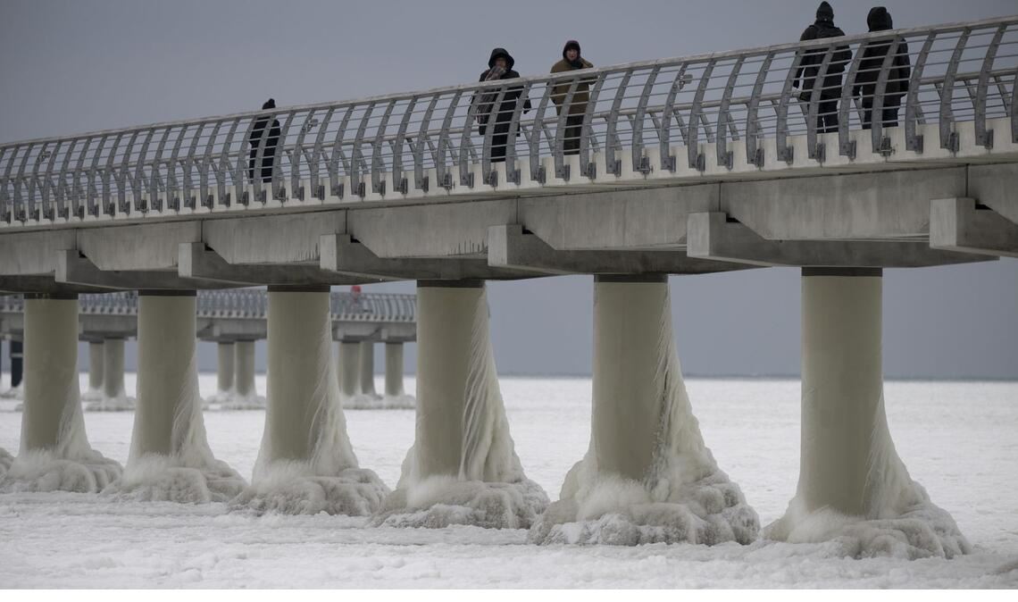 Menschen laufen am 4. Februar auf der eingefrorenen Seebrücke in Prerow. Die längste Seebrücke an der Ostseeküste ist komplett vom Eis umschlossen.