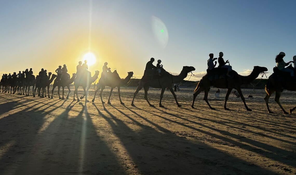 Menschen reiten auf Kamelen am Birubi Beach nördlich von Newcastle in Australien.
