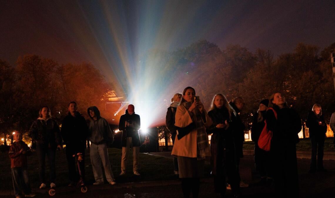 Menschen stehen vor einem Beamer, während der Berliner Dom bei der Generalprobe für das 21. Festival of Lights Berlin unter dem Motto „Let’s Shine Together“ angestrahlt wird.