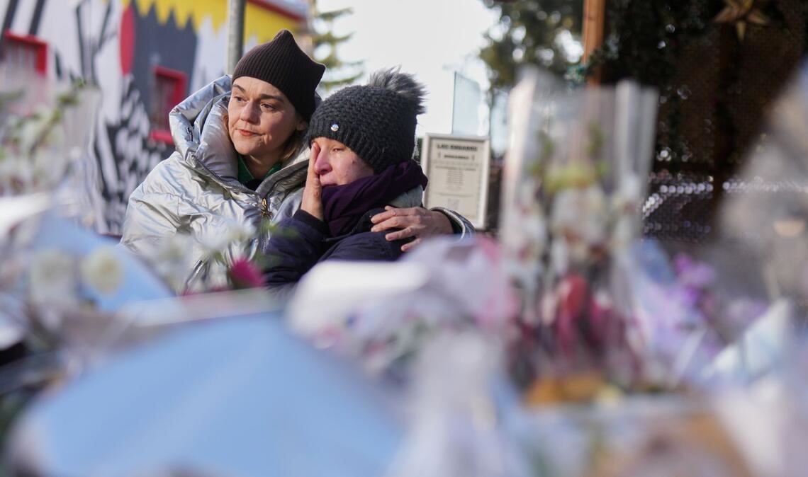 Menschen trauern hinter Blumen und Briefen in der Nähe der abgeriegelten Le Constellation Bar, wo ein verheerender Brand während der Neujahrsfeierlichkeiten Tote und Verletzte forderte.