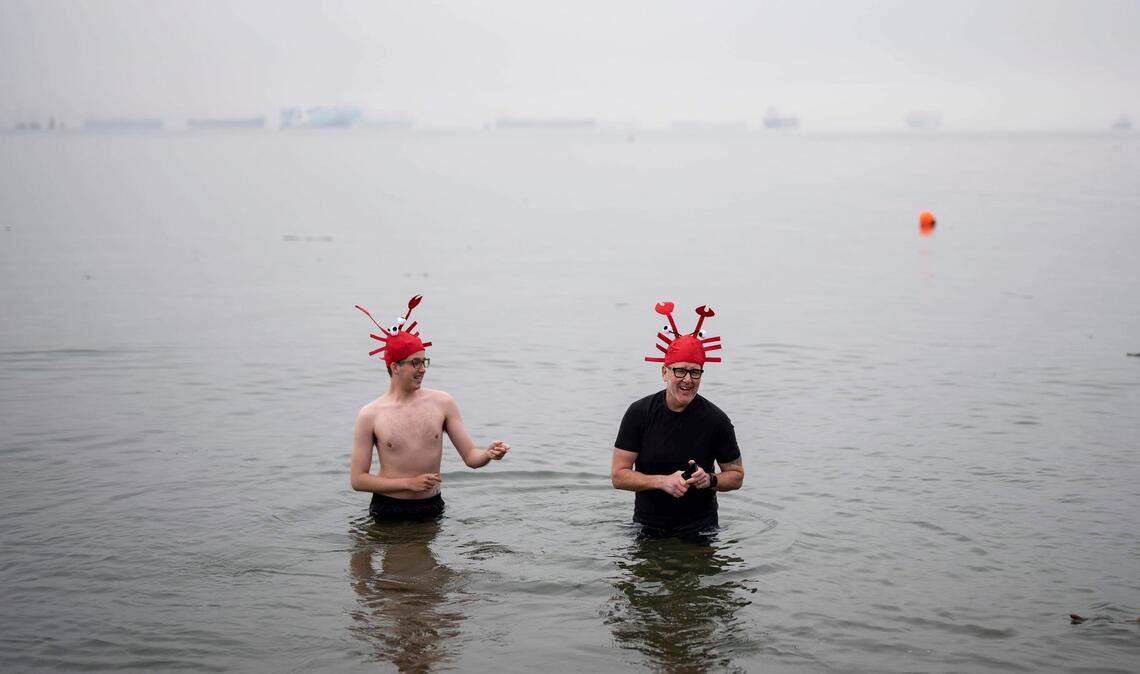 Menschen waten im Wasser während des olar Bear Swim in Vancouver.