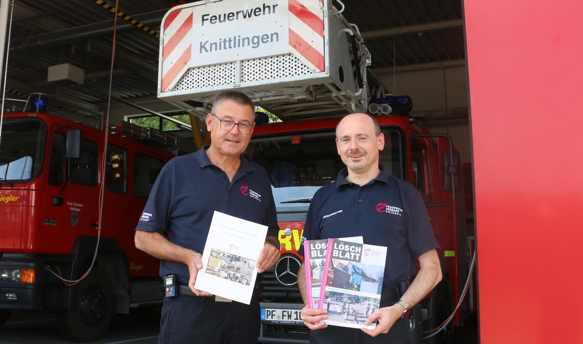 Michael Gutjahr (li.) und Markus Haberstroh vom Feuerwehrverband Enzkreis werben für die Feuerwehrarbeit und freuen sich auf die Leistungsschau. Foto: Deeg