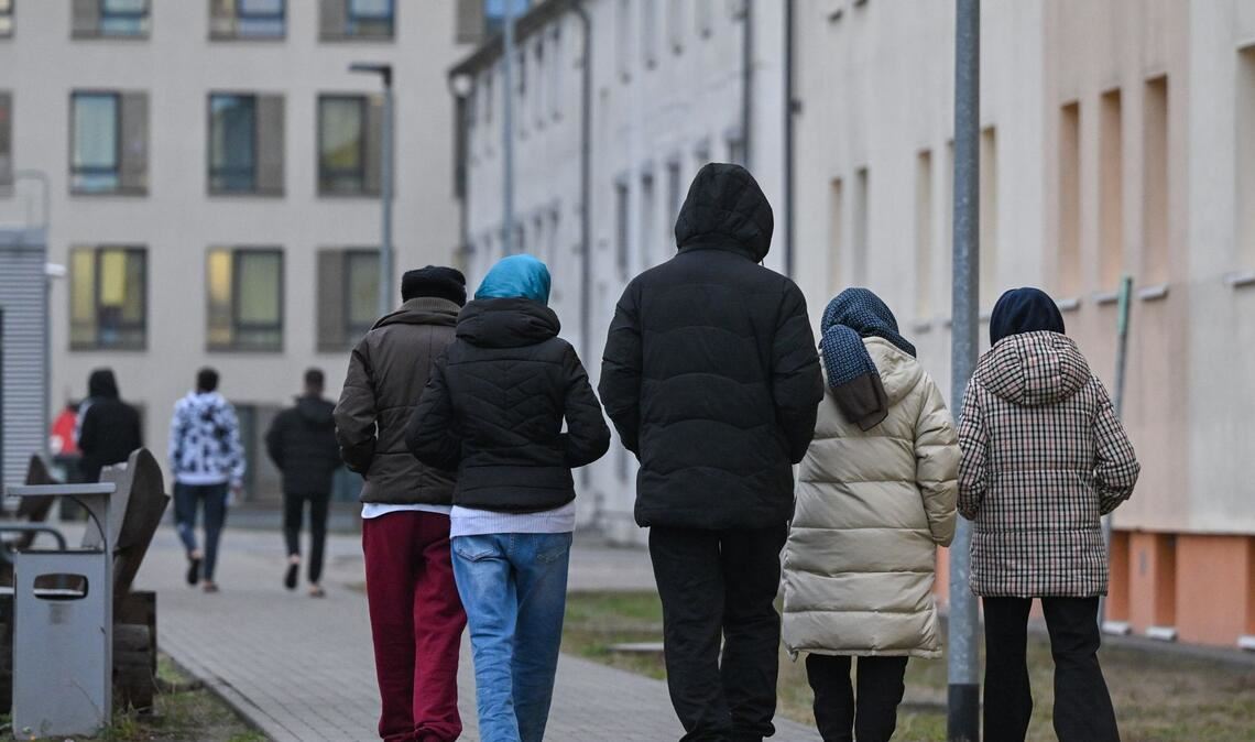 Migranten gehen über das Gelände einer Erstaufnahmeeinrichtung (Symbolbild).