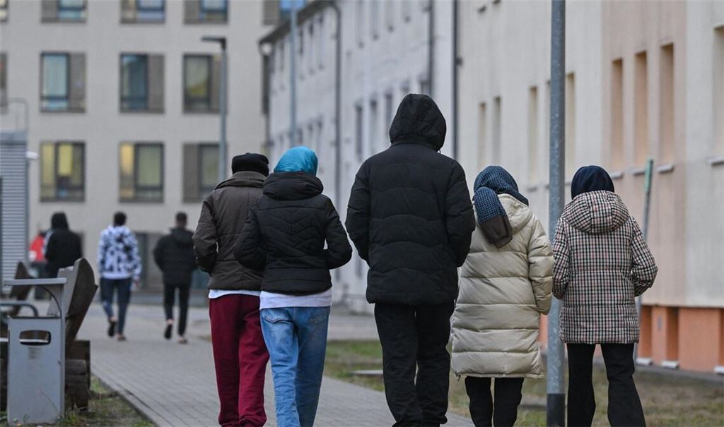 Migranten gehen über das Gelände einer Erstaufnahmeeinrichtung (Symbolbild).