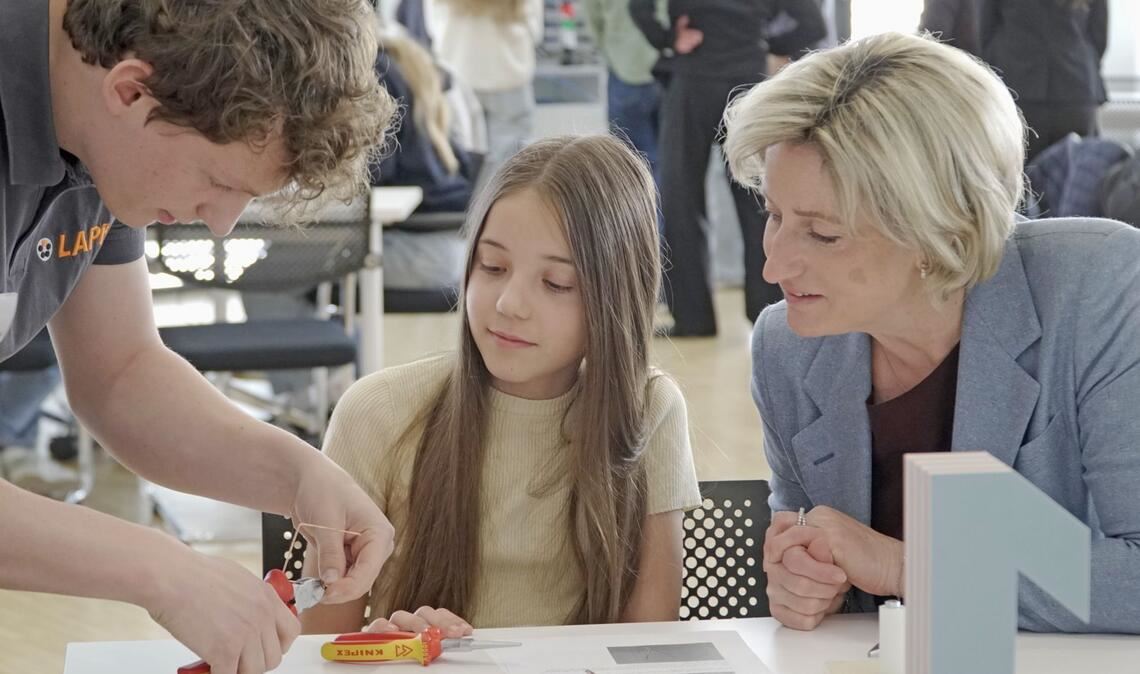 Ministerin Nicole Hoffmeister-Kraut mit der Sechstklässlerin Maria und dem Lapp-Azubi Sven Litterst beim Kupferdrahtbiegen.