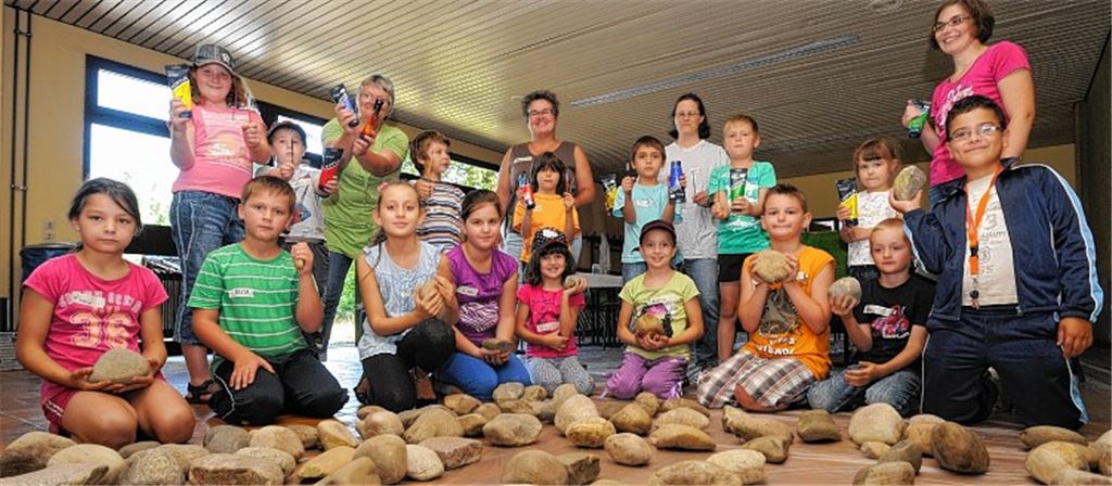 Mit Farbe und Pinsel machen sich die Kinder ans Werk, um Kieselsteine zu bemalen und damit ihre Faust-Schule zu verschönern.