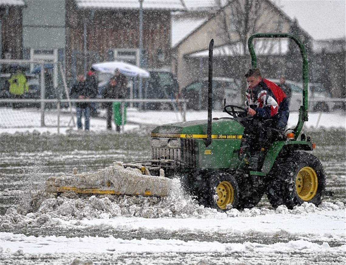 Mit Räumfahrzeugen und Schneeschippen machen die Helfer der SG Ölbronn-Dürrn den verschneiten Rasen bespielbar. Fotos: Fotomoment
