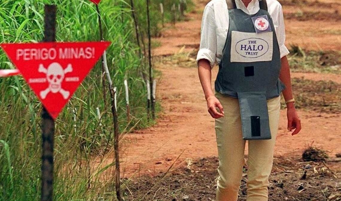 Mit Splitterschutz-Weste und Glasvisier geht Prinzessin Diana in Huambo in Angola durch ein Minenfeld, um zu erfahren, mit welchen Angstgefühlen die einheimische Bevölkerung leben muss.