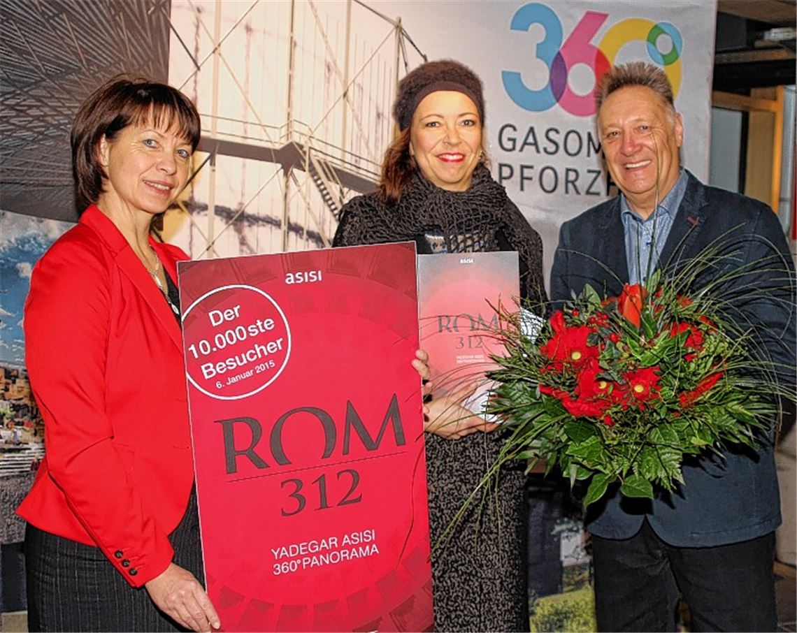Mit einer Jahreskarte für „Rom 312“, einem vom Künstler signierten Magazin sowie Blumen wurde die Jubiläumsbesucherin Susanne Schneider (Mitte) von Betriebsleiterin Angelika Taudien und Marketing-Koordinator Wolfgang Trautz überrascht. Foto: Kollros