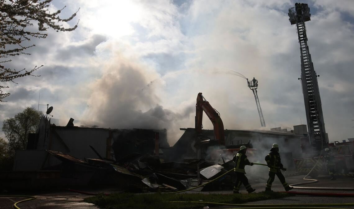 Mit schwerem Gerät arbeitet sich die Feuerwehr zu Glutnestern vor nach einem Brand in einem Club.