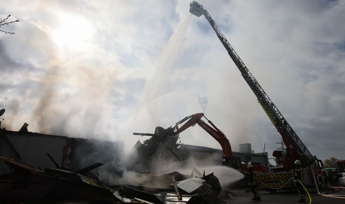Mit schwerem Gerät arbeitet sich die Feuerwehr zu Glutnestern vor nach einem Brand in einem Club.