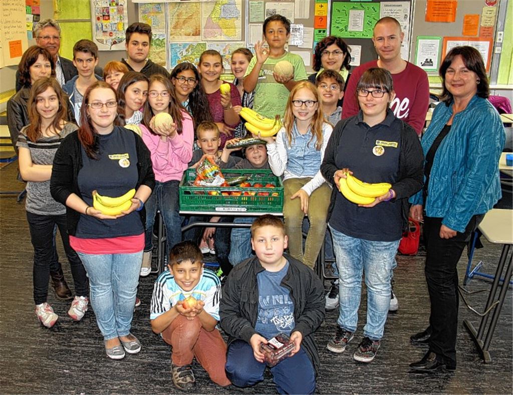 Mitarbeiterinnen des Edeka-Aktiv-Marktes übergeben die Obstkiste. Mit den Kindern und den Jugendbegleitern freuen sich die Vorsitzende des Fördervereins Petra Karst, Schulleiter Dr. Hans-Joachim Blum (hinten li.) und Konrektorin Andrea Maisel (re.).