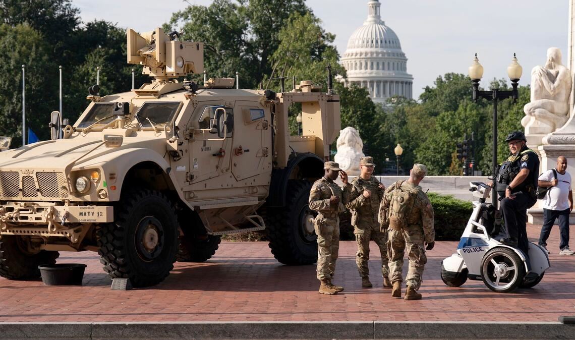 Mitglieder der Nationalgarde, die auf Anordnung von Präsident Trump in der US-Hauptstadt Washington sind, stehen neben einem gepanzerten Fahrzeug.