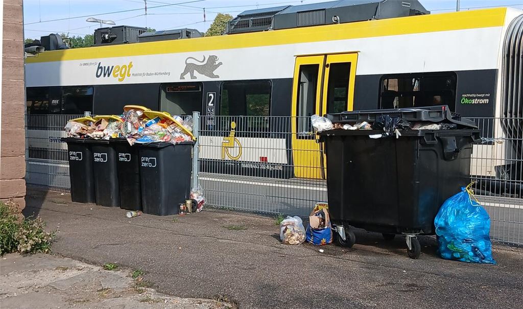 Momentaufnahme vom Dienstag: An Gleis 1 haben die Fahrgäste durch den Zaun hindurch einen freien Blick auf die übervollen Müllcontainer hinter der Flüchtlingsunterkunft. Fotos: Eier