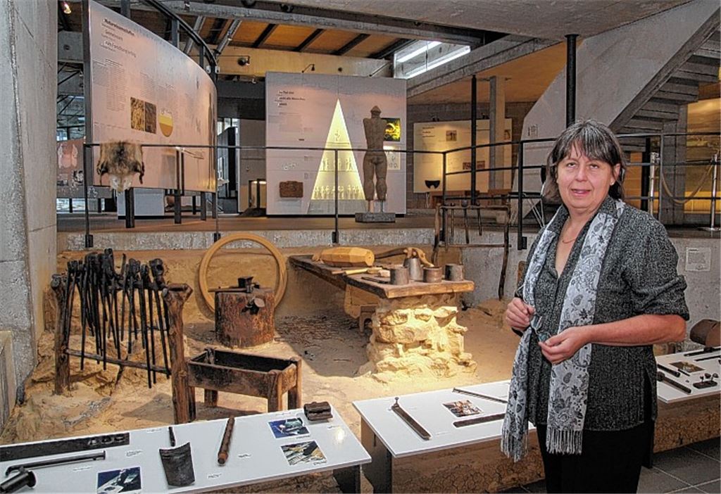 Museumschefin Dr. Simone Stork vor einer nachgebauten keltischen Schmiedewerkstatt. Kleines Bild oben: Grabbeigaben wie Nadeln mit Kugelköpfen aus Bernstein und korallenverzierte Toilettenbestecke. Unten: der Grabhügel. Fotos: Sadler (3), Museum (3)