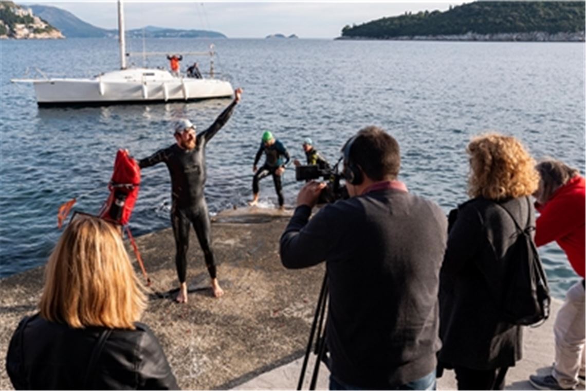 Nach 450 Kilometern, die Jonas Deichmann durch die Adria geschwommen war, kommt er in Dubrovnik an. Am Ende wurde er von zwei Einheimischen begleitet, die im Hintergrund aus dem Wasser steigen. Fotos: © Markus Weinberg 