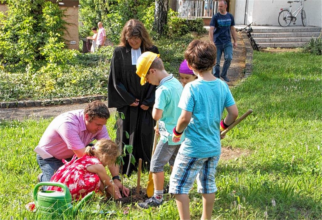 Nach dem Festgottesdienst pflanzen junge Gemeindemitglieder mit Pfarrerin Gabriele Goy einen Ginkobaum.