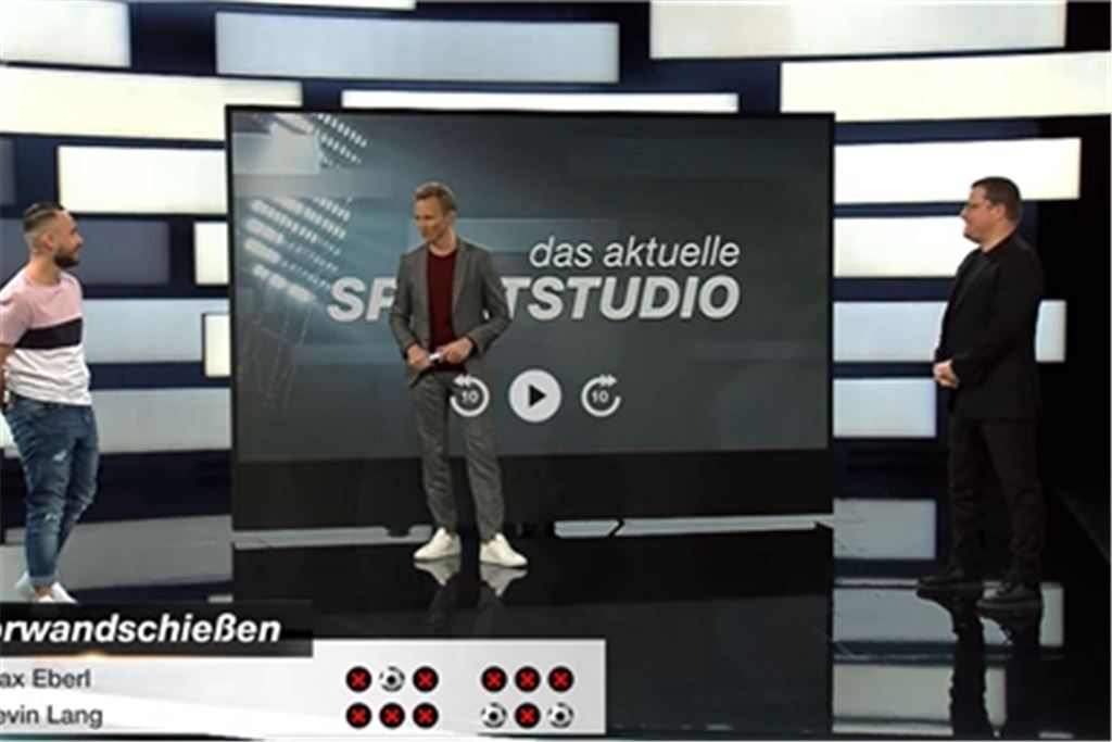 Nach dem Sieg an der Torwand: ZDF-Moderator Jochen Breyer Breyer (Mitte) gratuliert Kevin Lang (li.) zum Sieg gegen Max Eberl.Foto: Screenshot