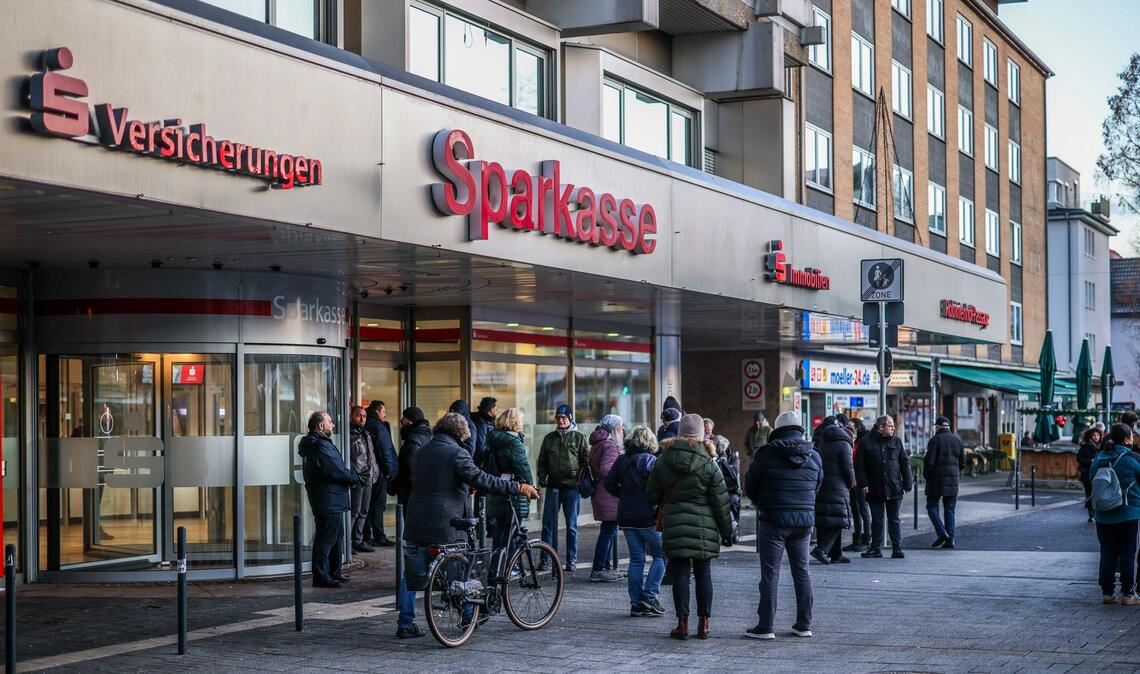 Nach einem Einbruch in den Tresorraum einer Bankfiliale in Gelsenkirchen warten Menschen vor dem Eingang auf Informationen.