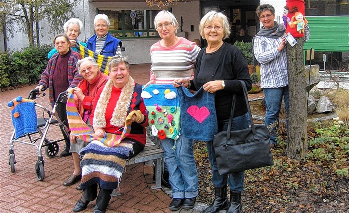Nach wenigen Wochen kann die Strickgruppe, die sich regelmäßig im Seniorenzentrum St. Franziskus trifft, schon auf viele bunte Ergebnisse verweisen. Eines davon befestigt Eike Fundinger vom Beratungszentrum consilio (re.) gerade an einem Baum im Eingangsbereich. Die Werke sollen auf die Kampagne „Demenz – Ansichtssache“ aufmerksam machen.