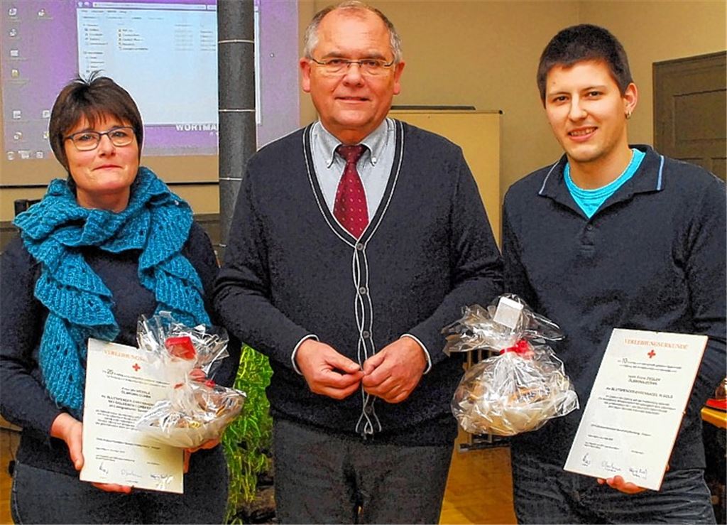Norbert Holme überreicht Ehrennadeln in Gold und ein Präsent der Gemeinde an Ute Wernle und Frank Ziegler (re.).Foto: Martin Schott