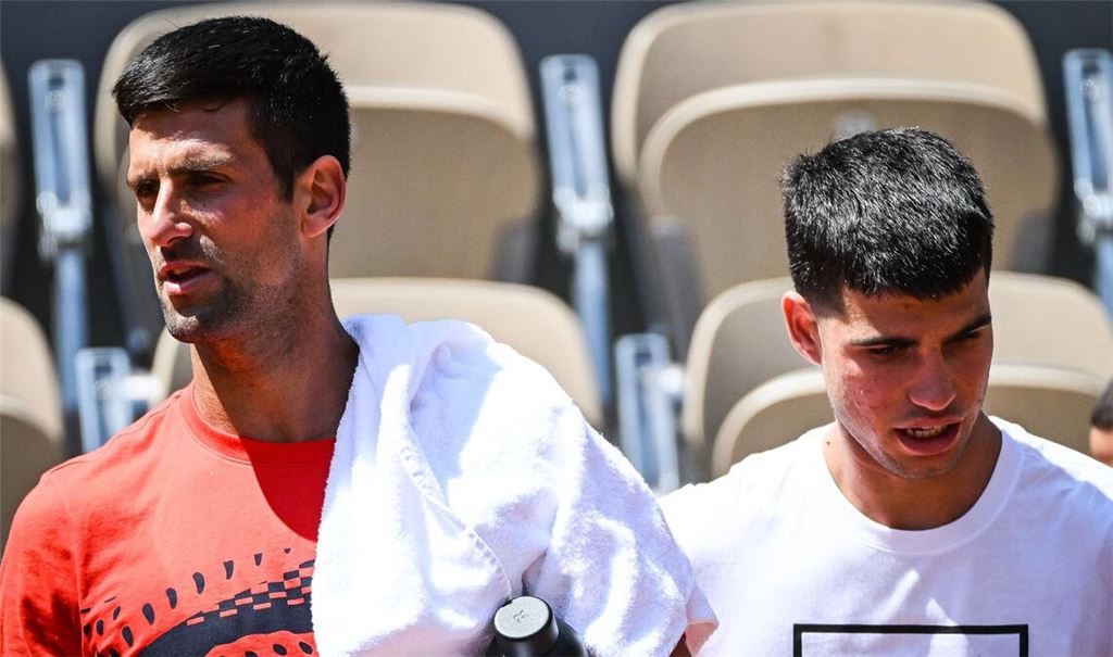 Novak Djokovic (l) aus Serbien und Carlos Alcaraz aus Spanien gehen nebeneinander während einer Trainingseinheit für die French Open 2023.