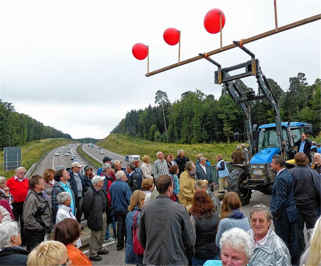 Nur eine Viertelstunde lang darf der Traktor inmitten der Menschenmenge auf der Brücke über der A8 parken und die roten Luftballons zeigen, die die Höhe der vom Regierungspräsidium angestrebten Trasse anzeigen.Foto: Roth