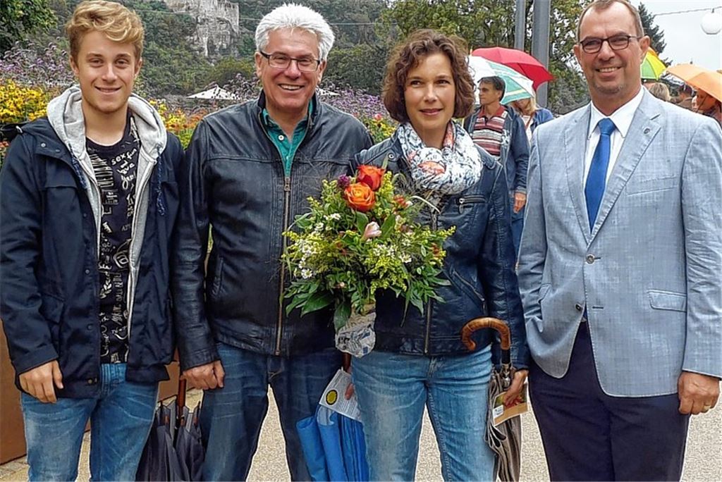 OB Frank Schneider (li.) übergibt Xandra Weber, die mit Ehemann und Sohn in die Enzgärten gekommen war, einen Blumenstrauß.