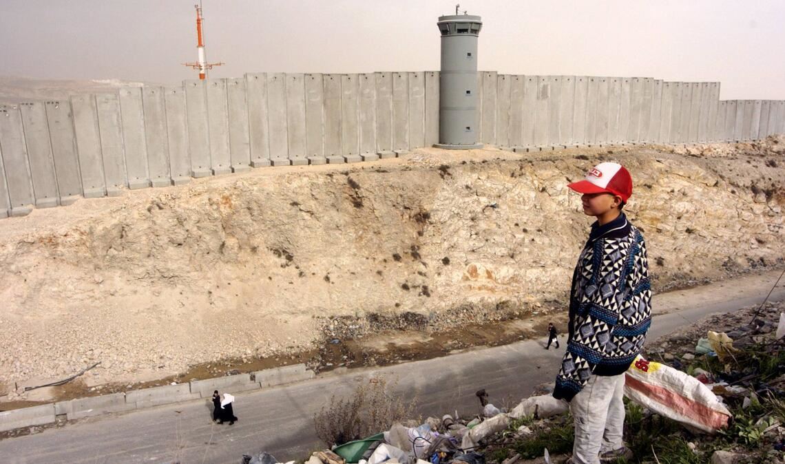 Palästinensischer Junge schaut auf eine Grenzmauer. Israels Regierung will Land im Westjordanland als „Staatseigentum“ registrieren (Archivfoto).