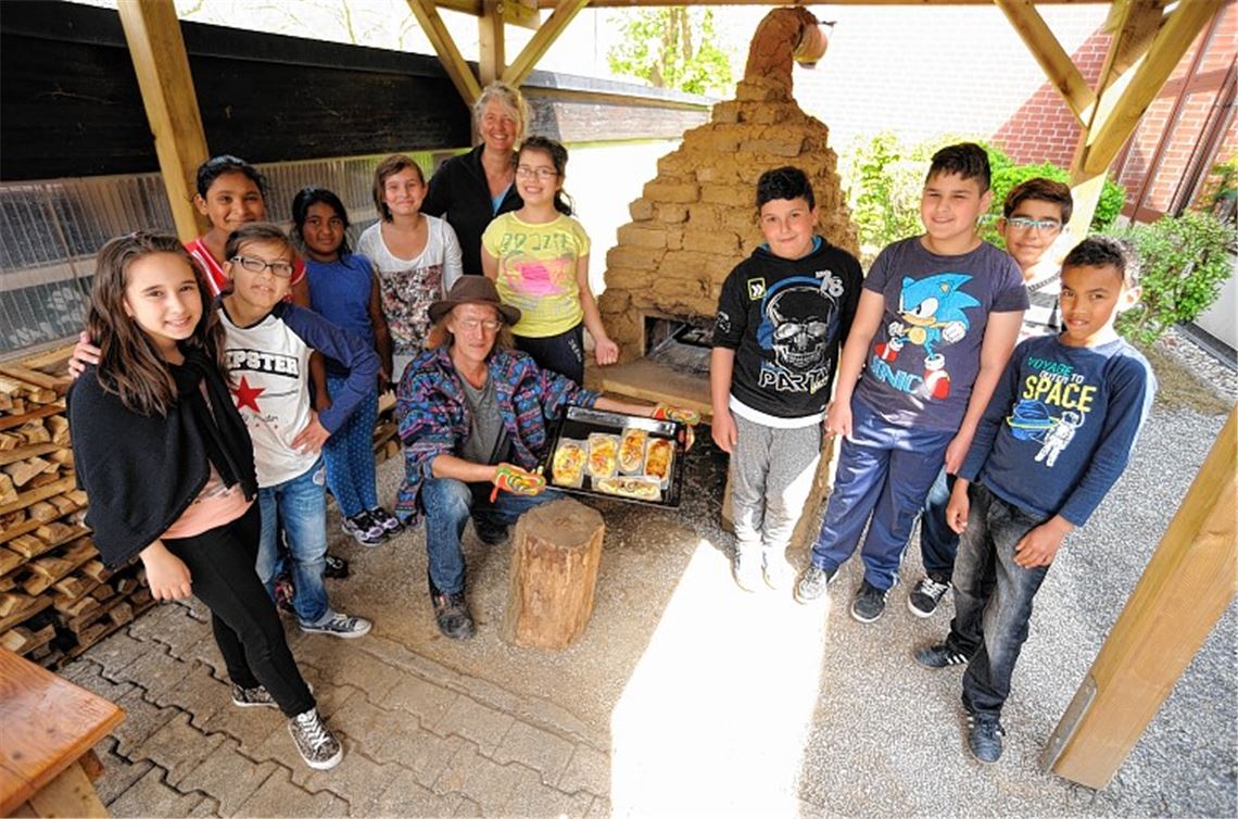 Paul Teschner (kniend) und Karin Arny (hinten stehend) haben mit Uhlandschülern einen Lehmofen gebaut.
