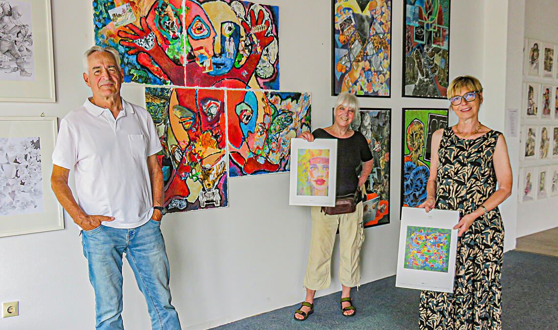 Peter Schumann, Bettina Rebhuhn und Bettina Wenz (re.) gehören zu den Kunstschaffenden, die derzeit eine Ausstellung in den ehemaligen Räumen des Malergeschäfts Geissel vorbereiten. Weitere Grafiker sind mit beteiligt, von denen auf diesem Foto Arbeiten ins Bild gehalten werden, die in einem Kalender der Gruppe abgedruckt worden sind. Foto: Becker