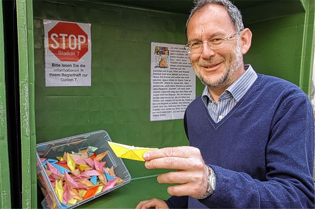 Pfarrer Hans Veit an der siebten Station des Osterwegs: Hier können Besucher auf einem Papierschiff beispielsweise notieren, welchen Stürmen sie in ihrem Leben ausgesetzt sind. 
