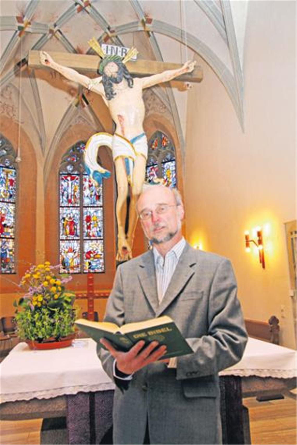 Pfarrer Wolfgang Schlecht von der evangelischen Kirchengemeinde Illingen vor dem Kruzifix der Cyriakuskirche in der Stromberggemeinde. Foto: Franz