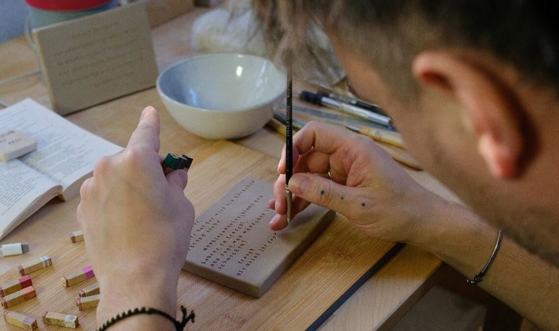 Phili bei der Arbeit. Wort für Wort wird „Faust I“ in feuchten Ton gestempelt. Foto: Silke Straube