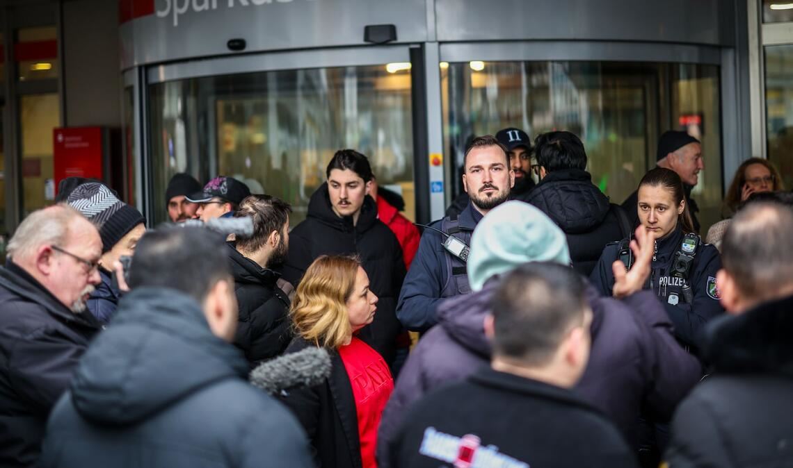 Polizeibeamte sprechen mit möglicherweise betroffenen Kunden der Sparkassenfiliale in Buer.