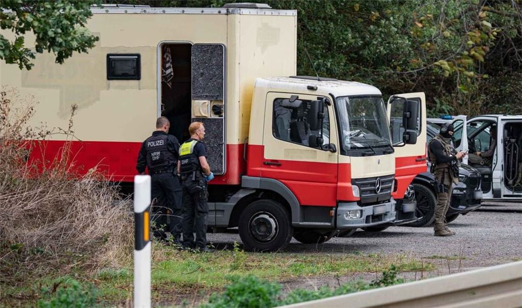 Polizisten in Spezialausrüstung sind an einem Lkw im Einsatz. Die Polizei hat laut NRW-Innenminister Reul in Niederzier das Fahrzeug des Verdächtigen für mehrere Sabotageaktionen gegen die deutsche Stromversorgung gestürmt.