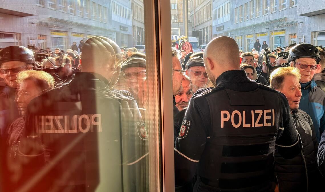 Polizisten sichern den Eingang der Sparkassenfiliale in Gelsenkirchen, vor der viele besorgte Kunde stehen und Informationen nach dem Einbruch in den Tresorraum verlangen.