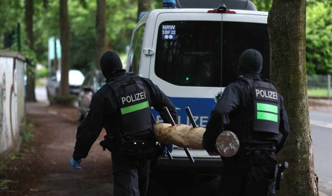 Polizisten tragen einen Rammbock.
