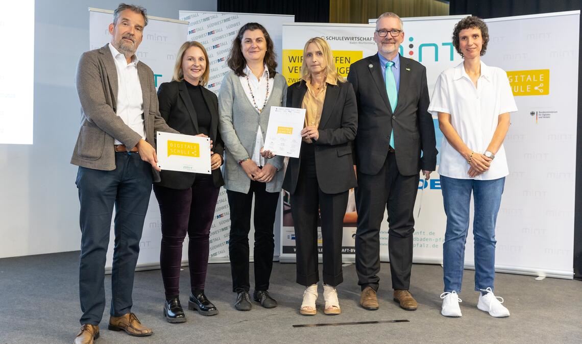 Preisübergabe: Die stellvertretende Schulleiterin Uta Talke-Trübenbach (4.v.li.) sowie die Projektbeauftragte Andrea Rosenbeiger-Ezzahoui (3.v.li.) nehmen die Auszeichnung „Digitale Schule“ aus den Händen von Staatssekretärin Sandra Boser (2.vli.), dem Geschäftsführer Politik, Bildung und Arbeitsmarkt der Unternehmer Baden-Württemberg, Stefan Küpper (li.), Harald Fisch von „MINT Zukunft“ und Sabine Becker von der VDI/VDE Innovation und Technik GmbH entgegen. Foto: Frank Eppler