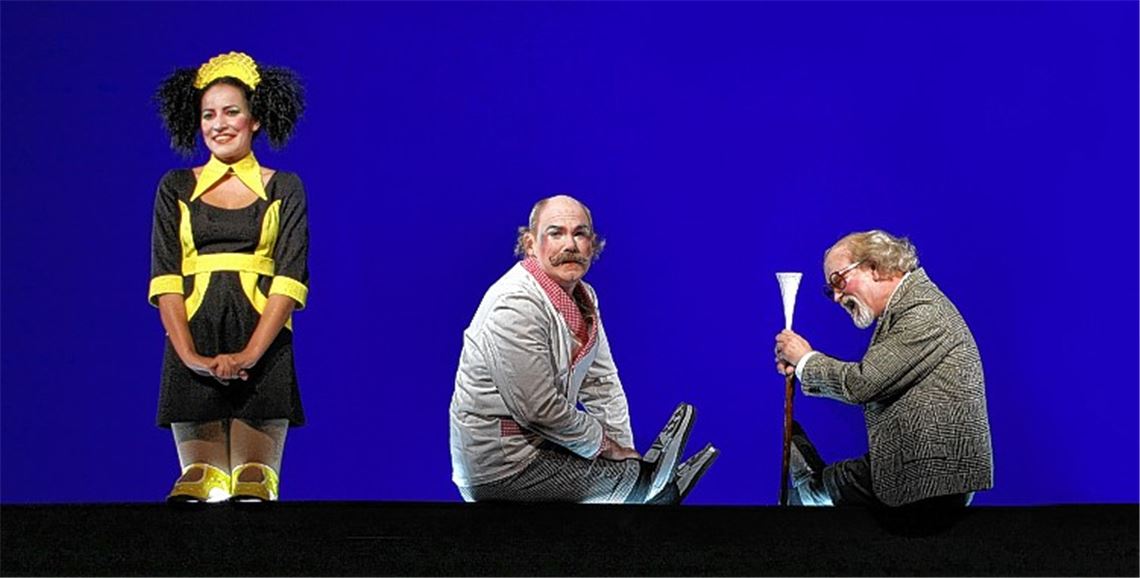 „Puppenspiel“ vor blauem Hintergrund mit echten Darstellern: Rashidah Aljunied (Blondina), Markus Löchner (Gundolf) und Holger Teßmann (Dr. Lombard, v.li.).
