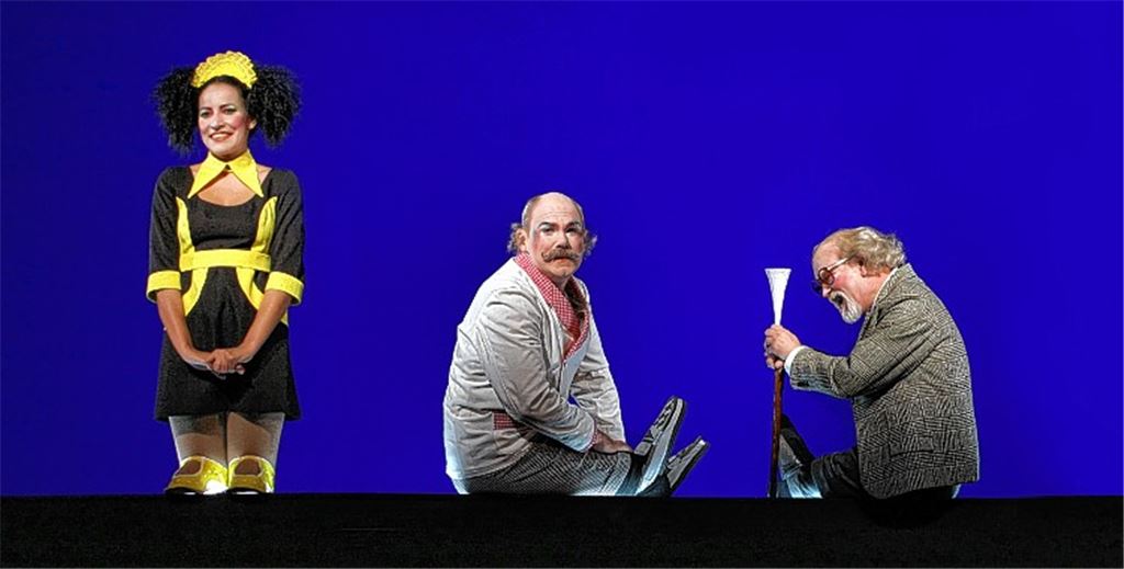 „Puppenspiel“ vor blauem Hintergrund mit echten Darstellern: Rashidah Aljunied (Blondina), Markus Löchner (Gundolf) und Holger Teßmann (Dr. Lombard, v.li.).