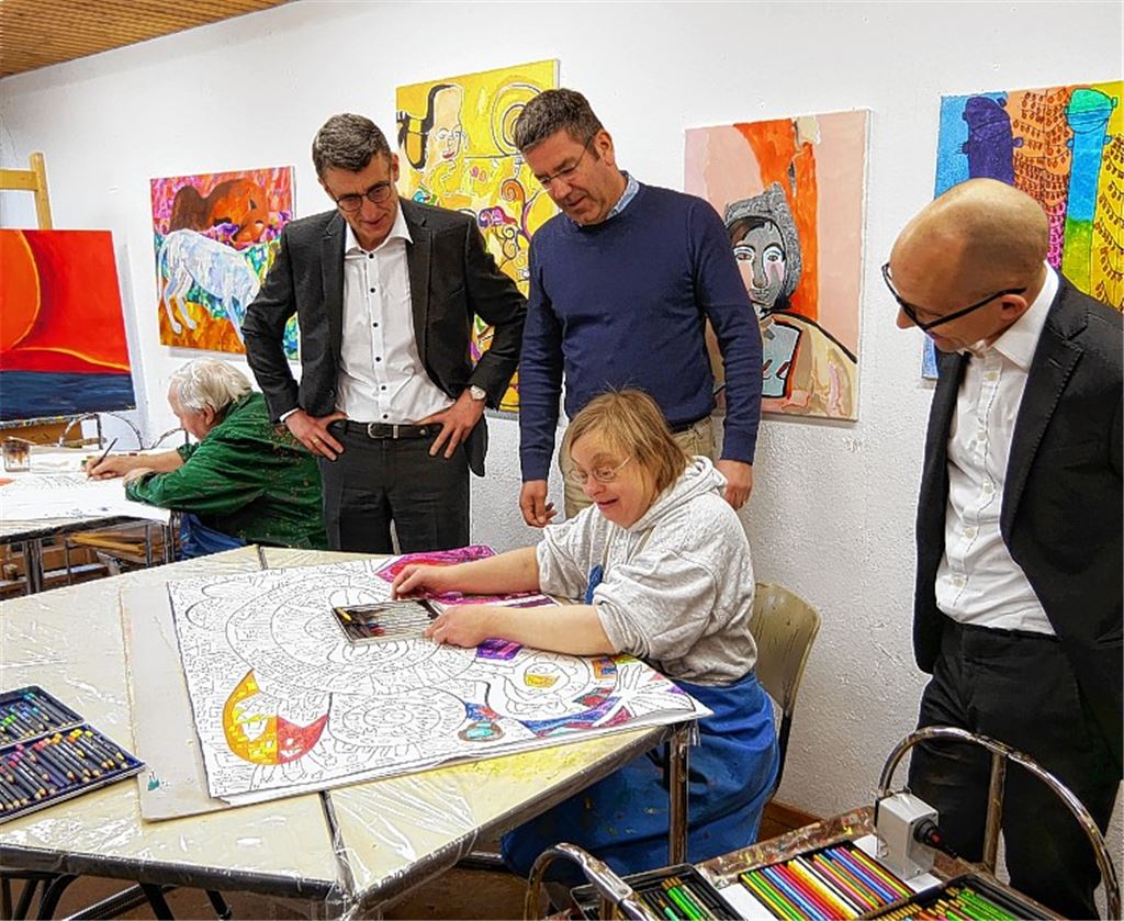 Ralf Günther-Schmidt (li.) und Timo Zimmermann (re.) besuchen die Kunstmanufaktur der Lebenshilfe mit deren Geschäftsführer Oliver Keppler (Mitte) und zwei Künstlern (sitzend).Friedrich