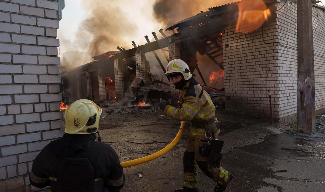 Rettungskräfte löschen ein Feuer in einer Kiewer Autowerkstatt, die durch einen russischen Angriff beschädigt wurde.